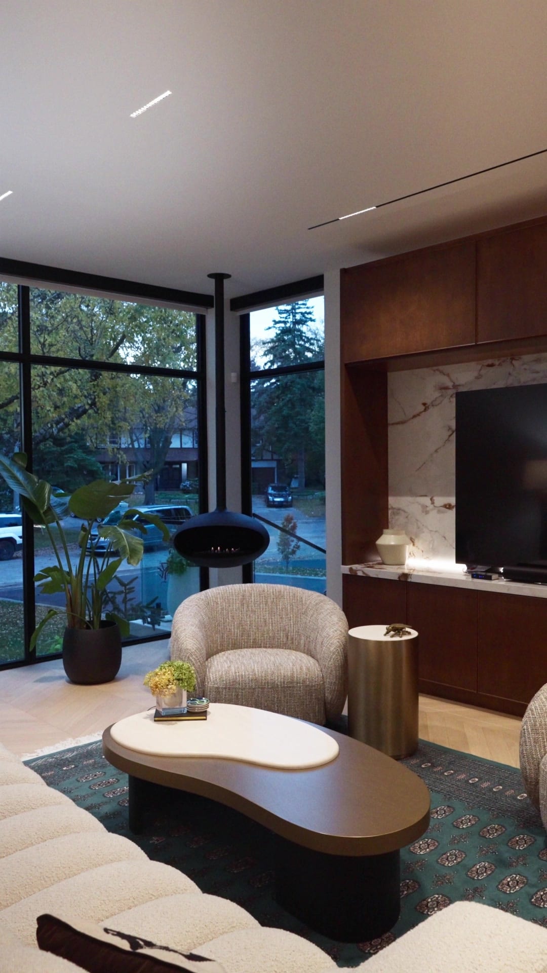 Corner sitting room with linear ceiling lighting and suspended fireplace