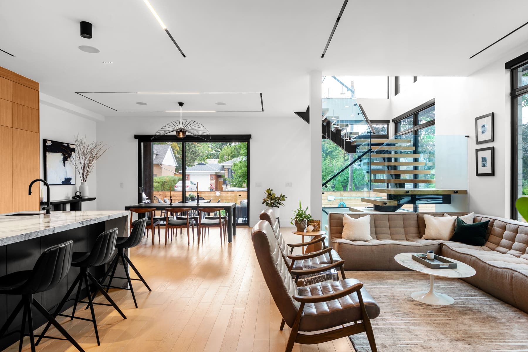 Open living and dining space with ceiling linear lighting and glass stair