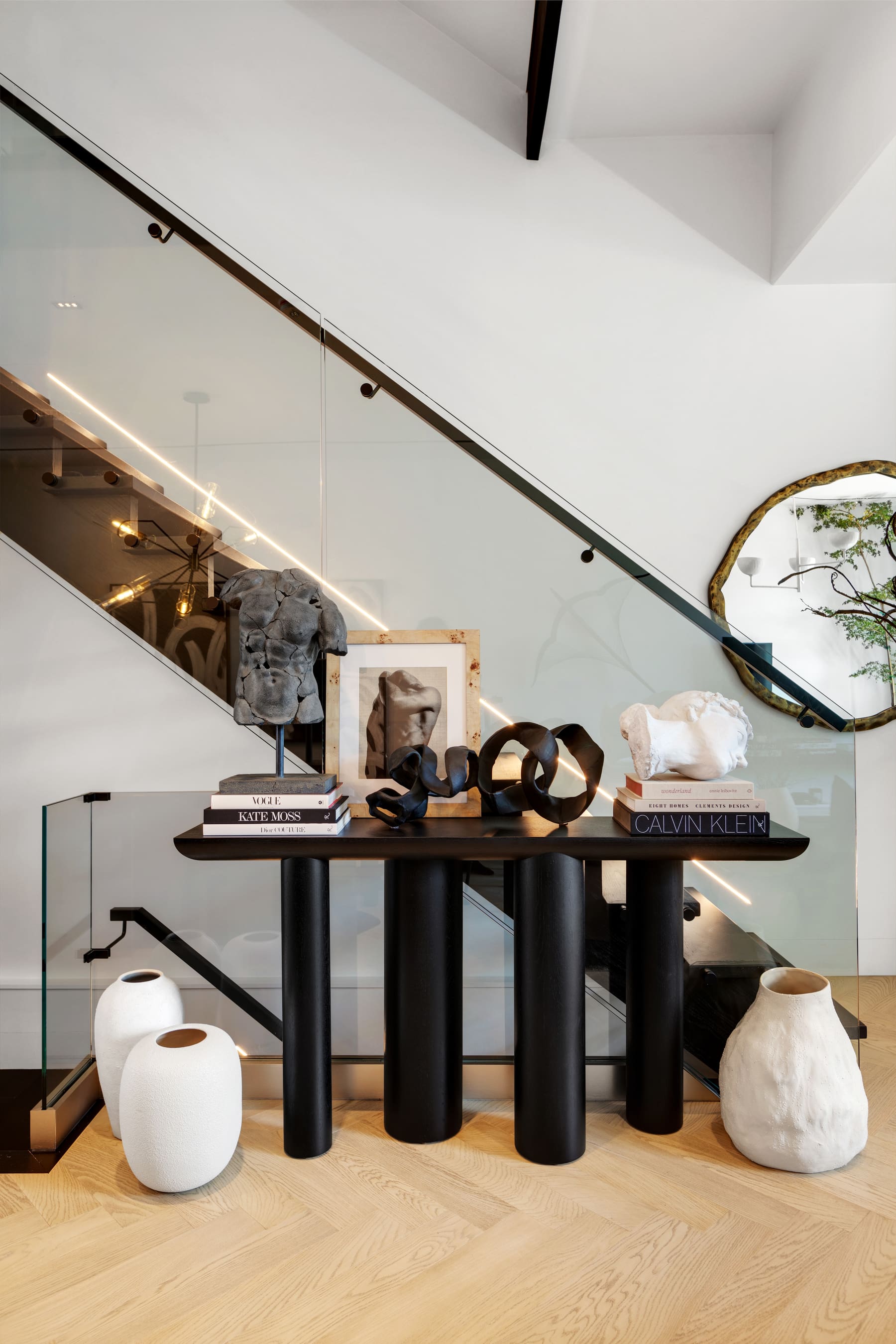 Sculptural console beside an illuminated glass stair